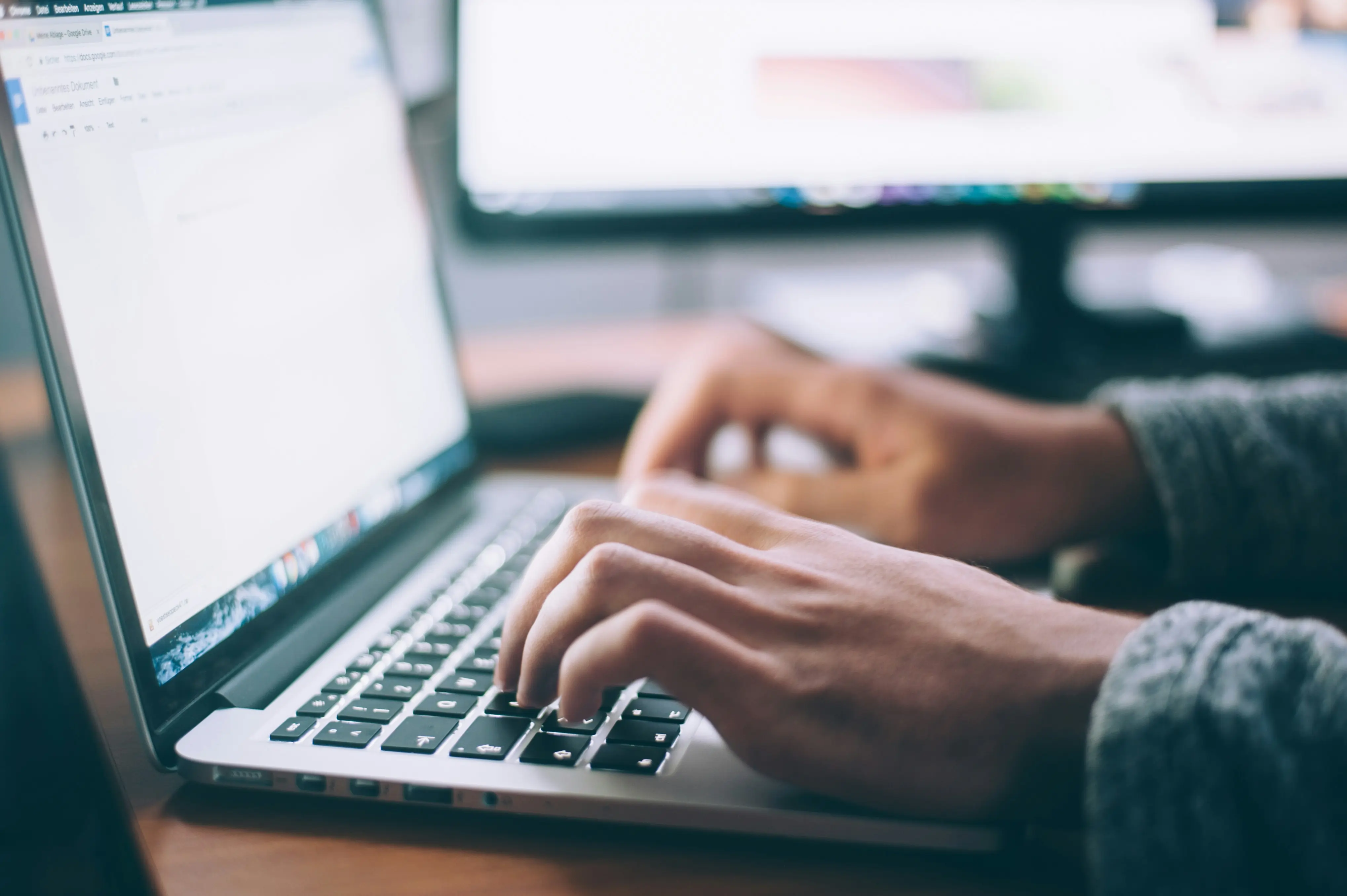 Two hands typing away on a laptop