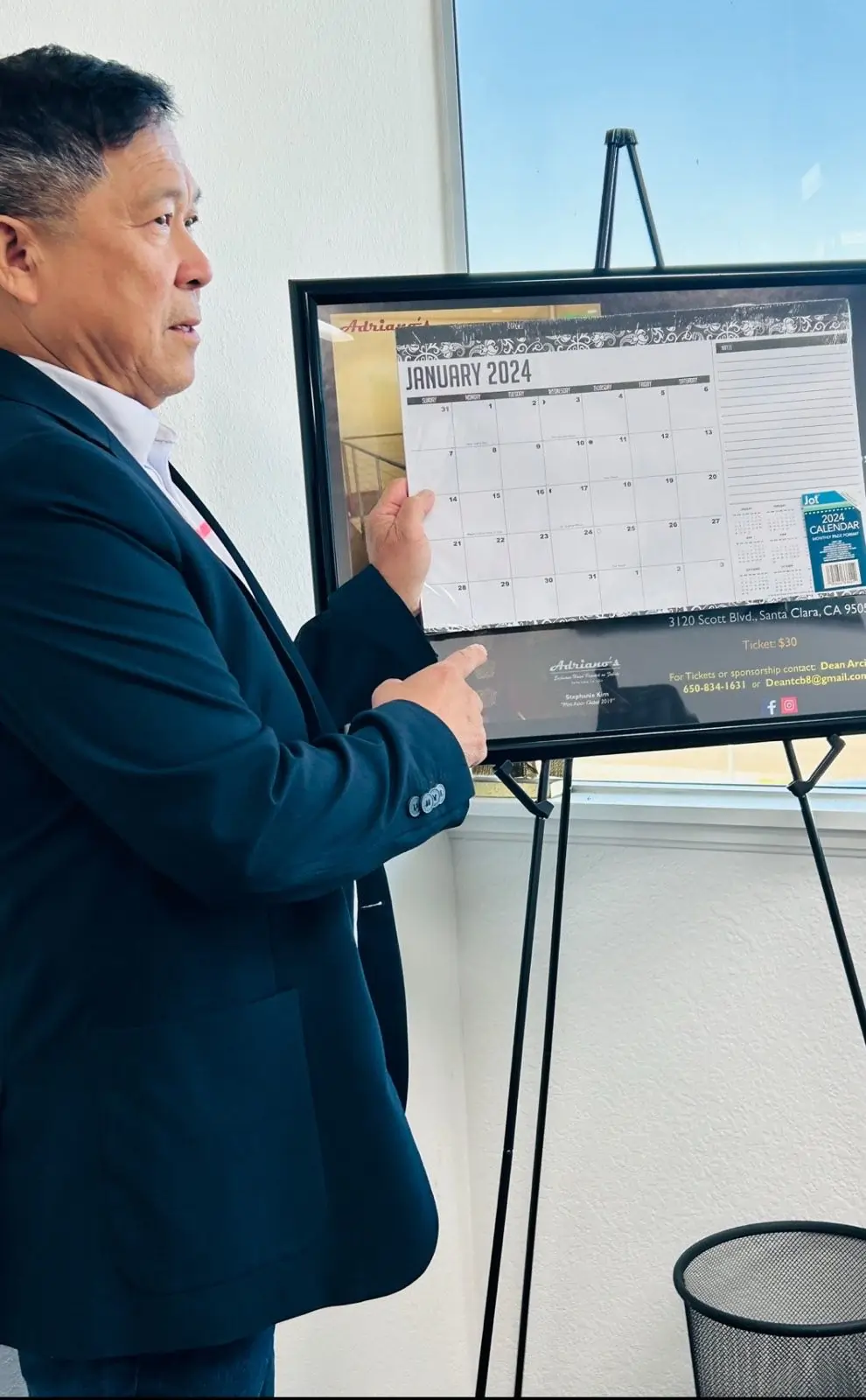 RDot Marketing's Founder Ramuel holding a calendar up on a board pointing to it with his index finger.